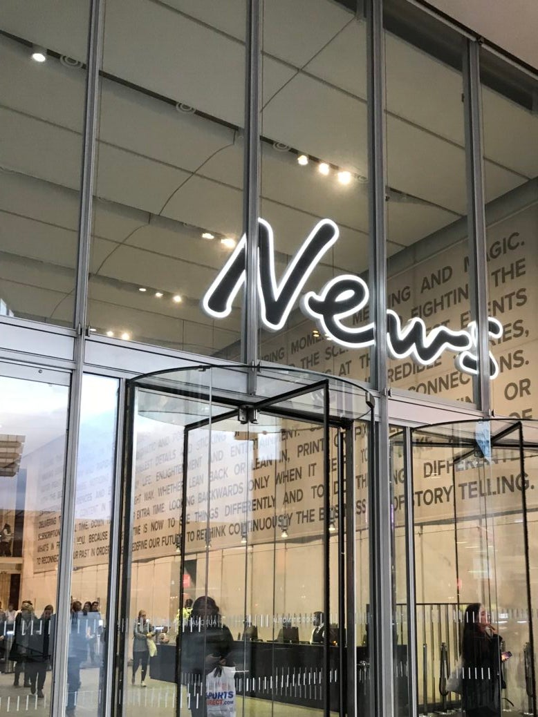 Entrance to News UK building with glass walls, revolving doors and a big sign saying 'News' over the doors