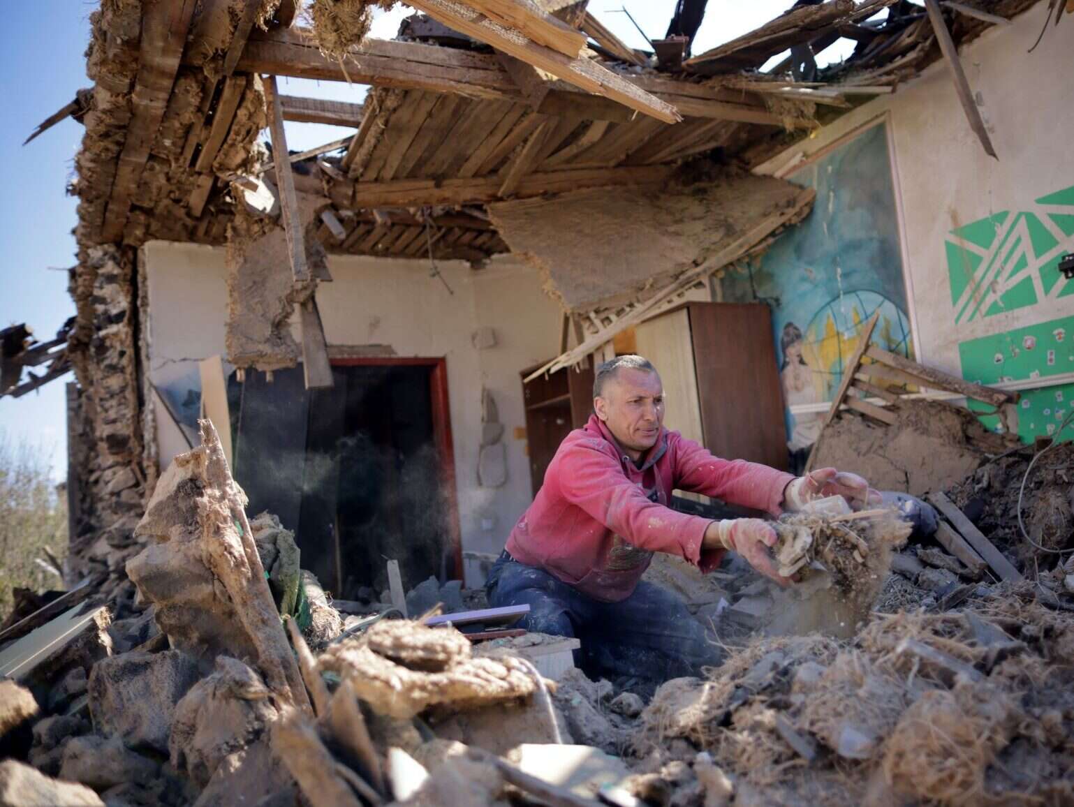 Ukrainian man removes debris from his damaged house|Civilians in Ukraine rely on local media to find safety from Russian attacks