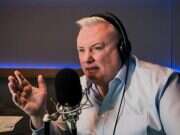 Stephen Nolan with headphones over his head, speaking into a microphone