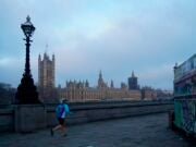 A jogger runs along the southern bank of the Thames with the Houses of Parliament across the river at sunrise, illustrating a story about the House of Lords Communications and Digital Committee's Future of News report, which makes recommendations to prevent the "fracturing" of the UK news environment.