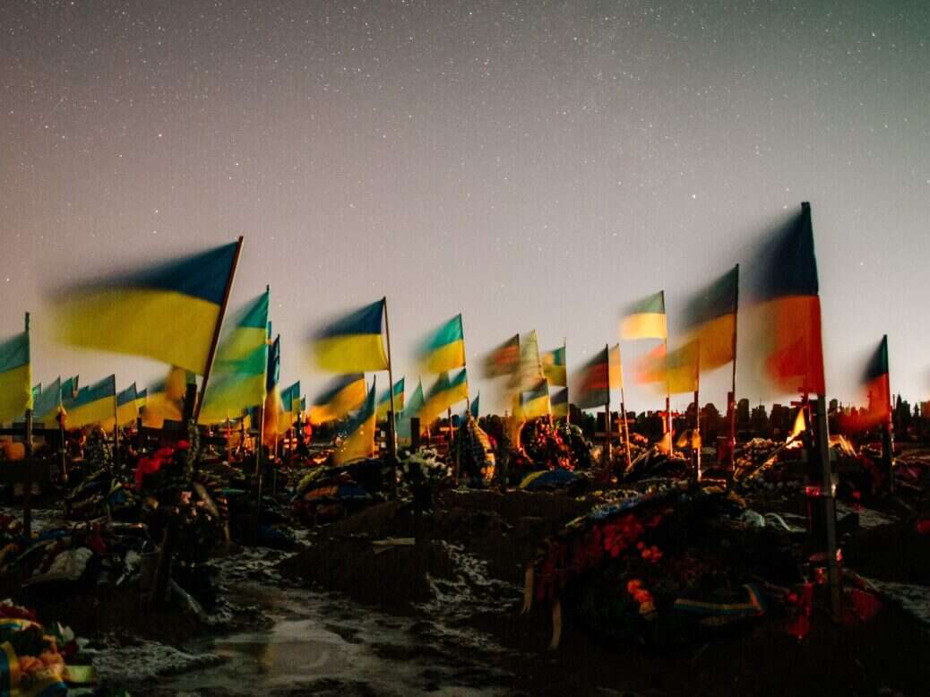 Ukrainian flags in the wind above the graves of fallen Ukrainian soldiers under the stars. (Photo by Pavlo Pakhomenko/NurPhoto via Getty Images)