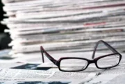 Reading glasses in front of a pile of newspapers