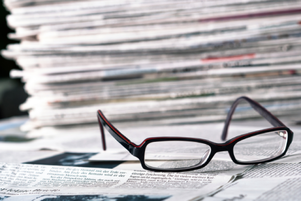 Reading glasses in front of a pile of newspapers