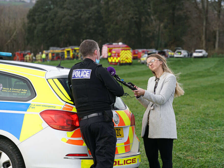 A local radio journalist interviews a police officer, illustrating a story about the costs that go into employing a Local Democracy Reporter