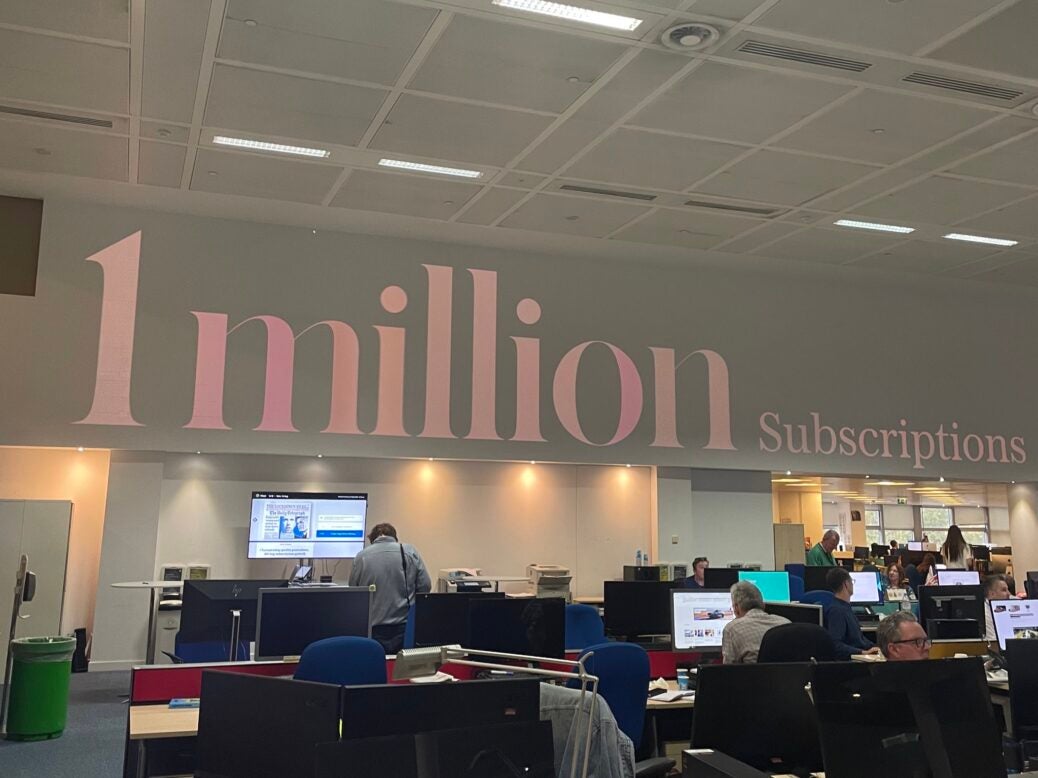 The words '1 million subscriptions' appear projected onto the wall of The Telegraph offices.
