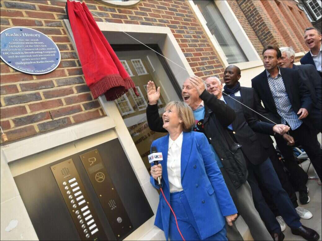 Former LBC staff pull the curtain aside on a plaque commemorating 50 years since the station's launch.