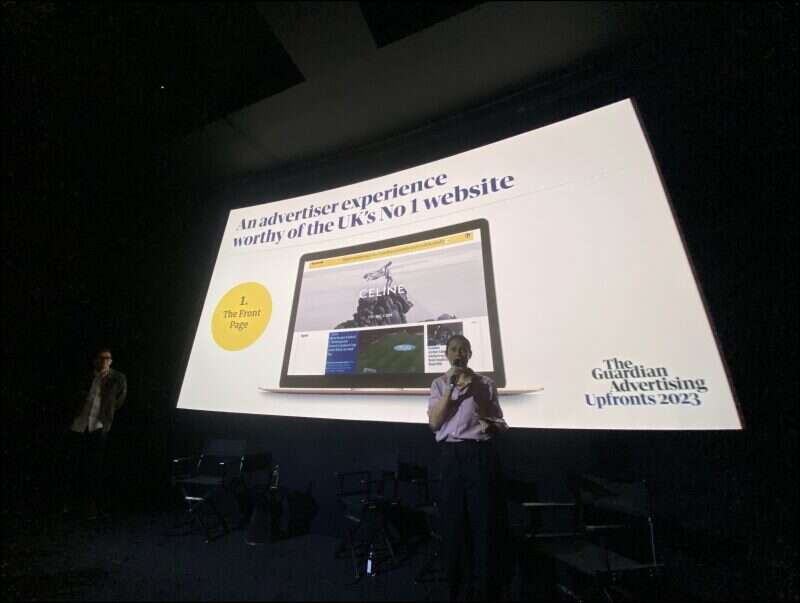 Guardian director of clients, marketing and research James Fleetham (left) and chief advertising officer Imogen Fox (right) stands in front of a screen at the publisher's advertiser upfront at the Curzon Bloomsbury, London, in November 2023. The slide behind them displays the new front page banner ad format on a laptop. Picture: Press Gazette