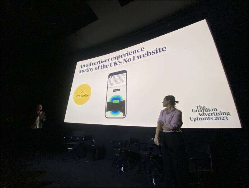 Guardian director of clients, marketing and research James Fleetham (left) and chief advertising officer Imogen Fox (right) stands in front of a screen at the publisher's advertiser upfront at the Curzon Bloomsbury, London, in November 2023. The slide behind them displays the new "interscroller" advertising format on a phone. Picture: Press Gazette