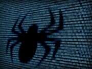 The silhouette of a spider is formed by gaps in binary code, illustrating an article about which top news sites have blocked the web crawlers used by artificial intelligence (AI) companies to feed their large language models.