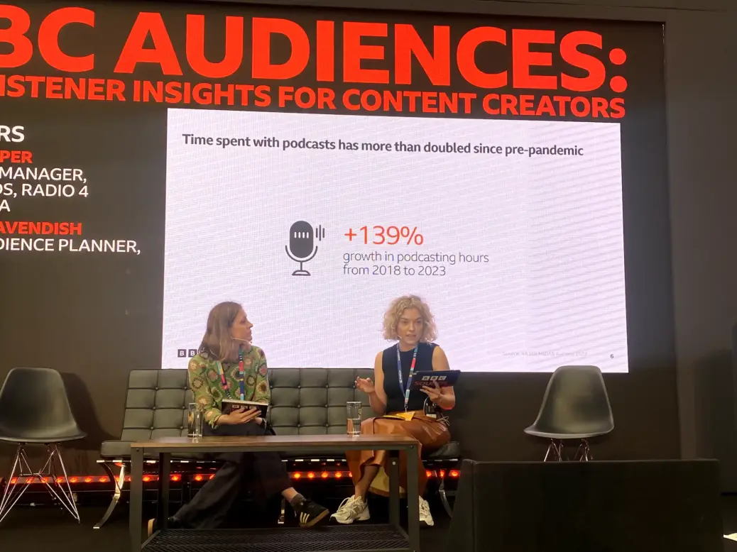 BBC Audio senior audience planner Georgie Cavendish (left) and BBC Sounds, Radio 4 and 4Extra research manager Grace Jasper (right) appear on stage at the BBC Sounds stage at The Podcast Show 2024 where they talk through the BBC's UK podcast audience data.
