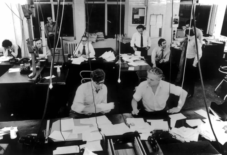 Image of Evening Standard newsroom in the 1970s featuring 10 members of staff and a lot of desks covered in paper