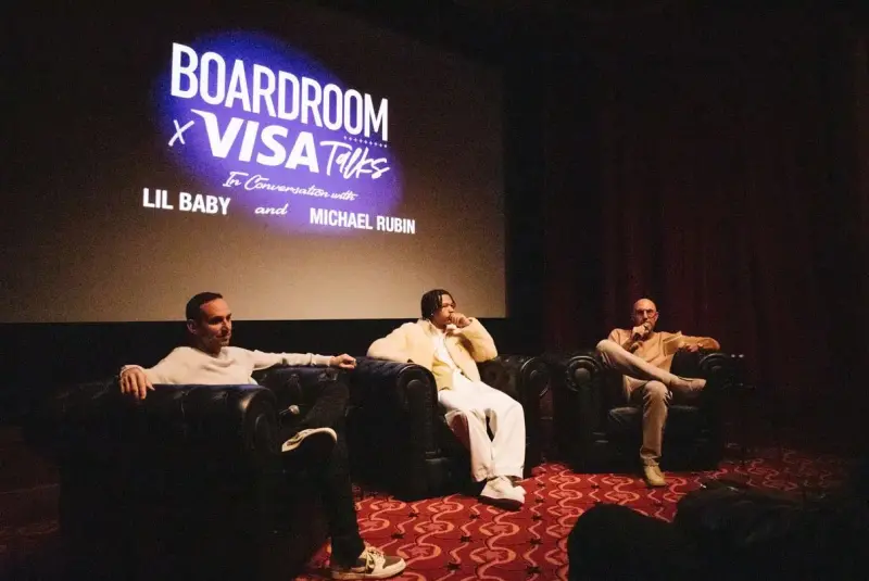 Michael Rubin, Lil Baby, Rich Kleiman at the Boardroom x Visa Talks event. Men pictured in armchairs with the corner of the audience in shot and a projected Boardroom x Visa Talks logo behind them