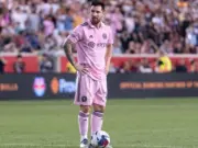 Lionel Messi in pink Inter Miami kit on pitch with football at his feet and hands on hips