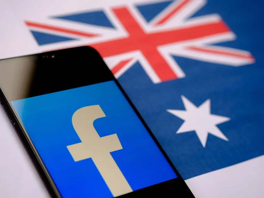 Facebook logo seen on a smartphone screen and blurred Australian flag on the background