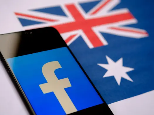 Facebook logo seen on a smartphone screen and blurred Australian flag on the background