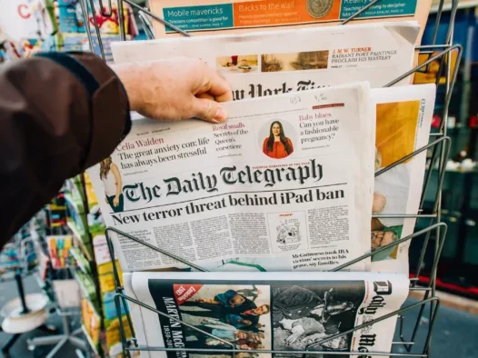 A person pulls a copy of The Daily Telegraph, with title New Terror ban of iPad, out from a newsstand. The picture illustrates a story about IPSO's annual report for 2023, which combined with publisher statements for 2023 reveals that The Daily Telegraph had the most rulings upheld against it during the year.