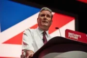 Sir Keir Starmer appears speaking to the 2023 Labour Party conference, sleeves rolled up and covered in glitter from a recent protest.