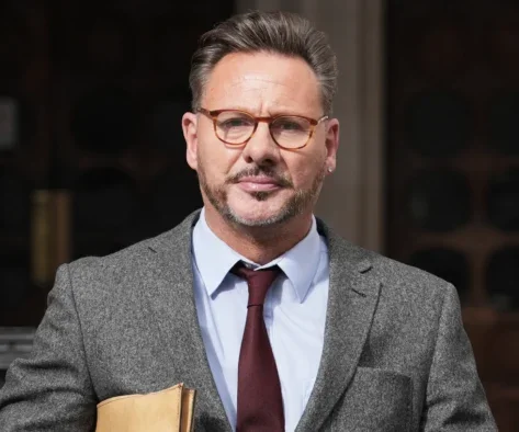 Picture shows Glenn Mulcaire outside a court building dressed in a suit and holding a document folder