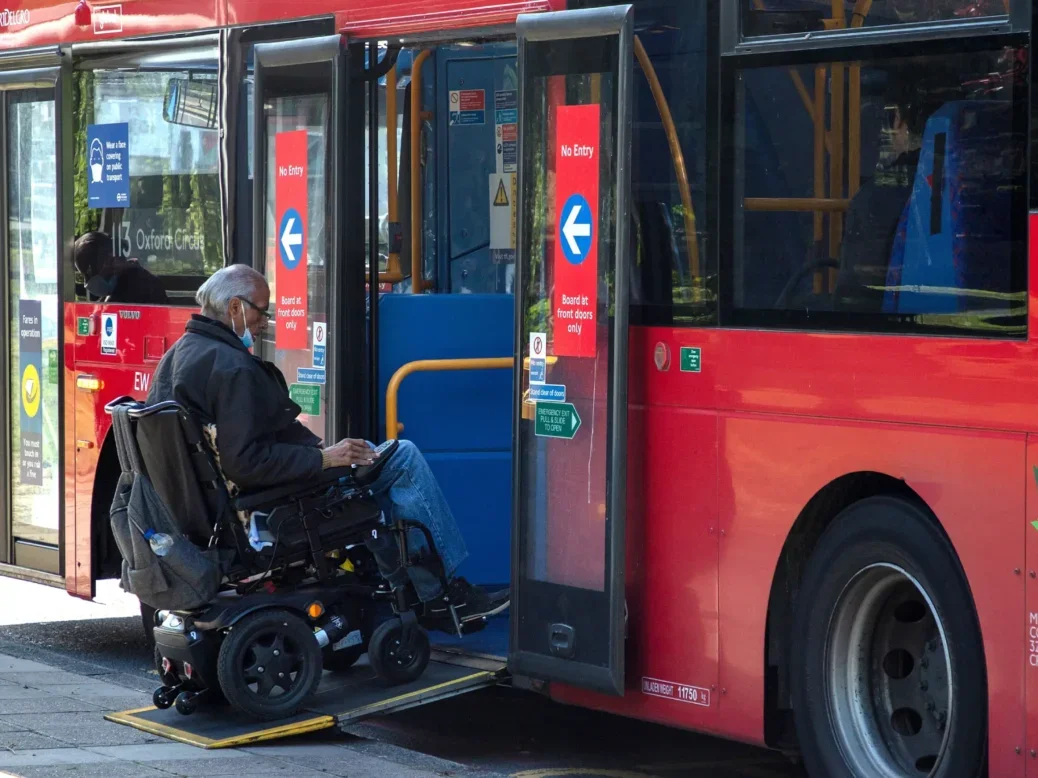 Man in wheelchair boards a bus using its ramp. Picture: Shutterstock/Joe Kuis