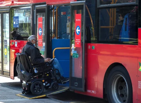 Man in wheelchair boards a bus using its ramp. Picture: Shutterstock/Joe Kuis