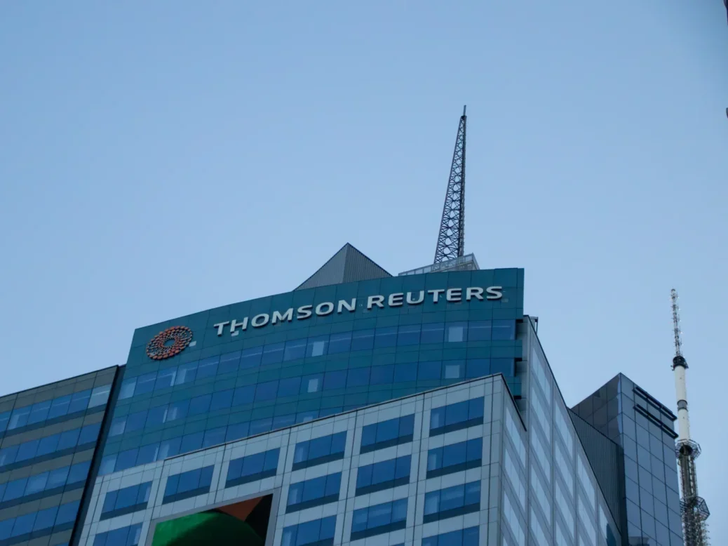 Top of Thomson Reuters building with its logo on and grey sky in background