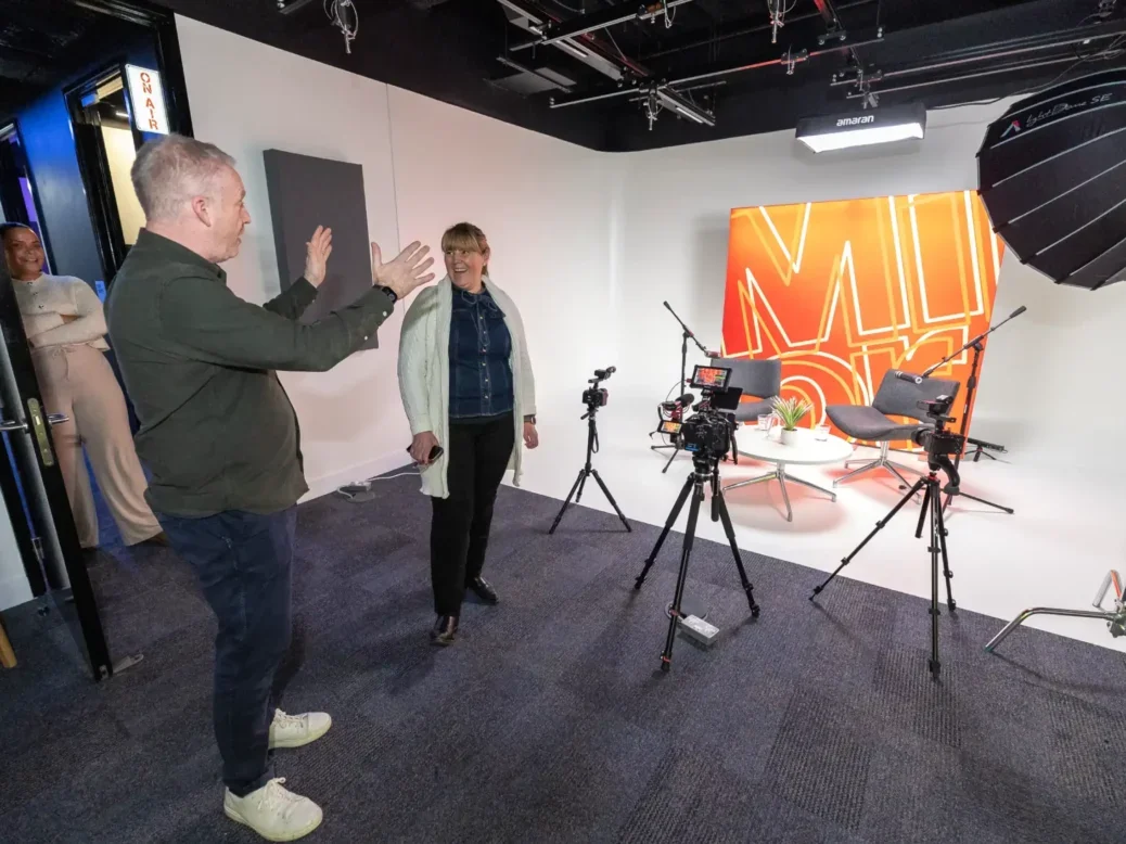 Mark Field, director of Reach Studio, gestures to two members of staff inside large video studio set up with Mirror branding