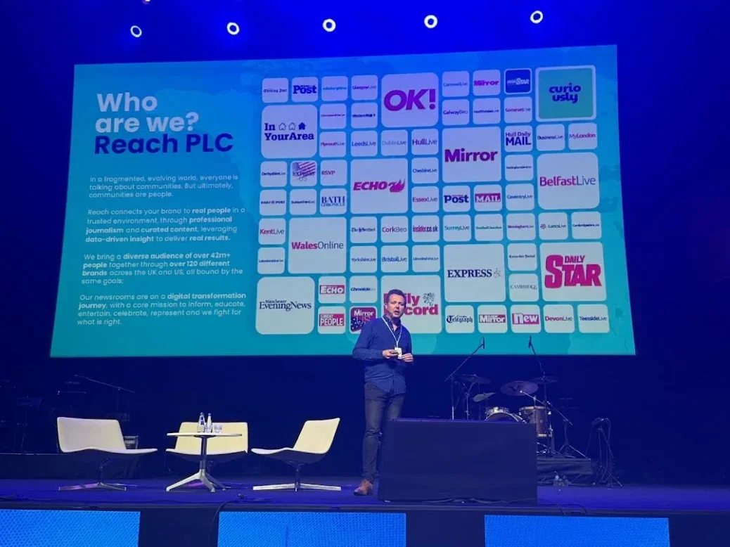 Reach audience director (distribution) Martin Little on stage at the WAN-IFRA World News Media Congress with a slide behind him showing logos of many Reach brands