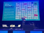 Reach audience director (distribution) Martin Little on stage at the WAN-IFRA World News Media Congress with a slide behind him showing logos of many Reach brands