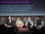Left to right: CNN chief executive Mark Thompson, BBC News chief executive Deborah Turness, The Economist editor-in-chief Zanny Minton Beddoes and BBC analysis editor Ros Atkins. The three executives are visibly mid-disagreement: Minton Beddoes is gesticulating with her hands apart as though making a firm point, Turness looks taken aback and Thompson is leaned back casting a single hand up with the fingers splayed as though to suggest he is either taking the point or thinks it's immaterial.