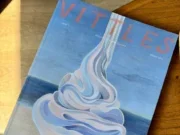 Front cover of Vittles magazine sitting on a wooden table. The cover has a seaside background in a painted style with beach, sea and sky with a massive Mr Whippy style ice cream in the foreground