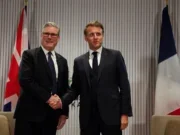Prime Minister Sir Keir Starmer shakes hands with France's President Emmanuel Macron as they stand in front of UK and French flags