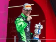Formula 1 Kick Sauber driver Nico Hulkenberg, wearing green race suit, Pirelli hat and holding a Lego trophy, getting his first podium at the British Grand Prix on 6 July 2025