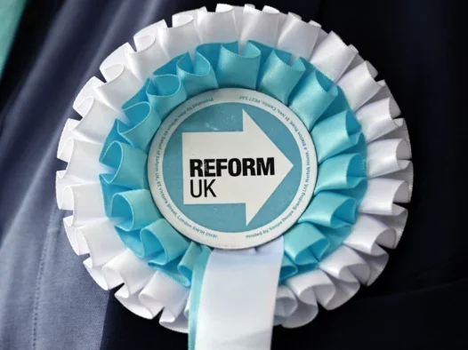 Reform UK rosette pinned to a suit jacket
