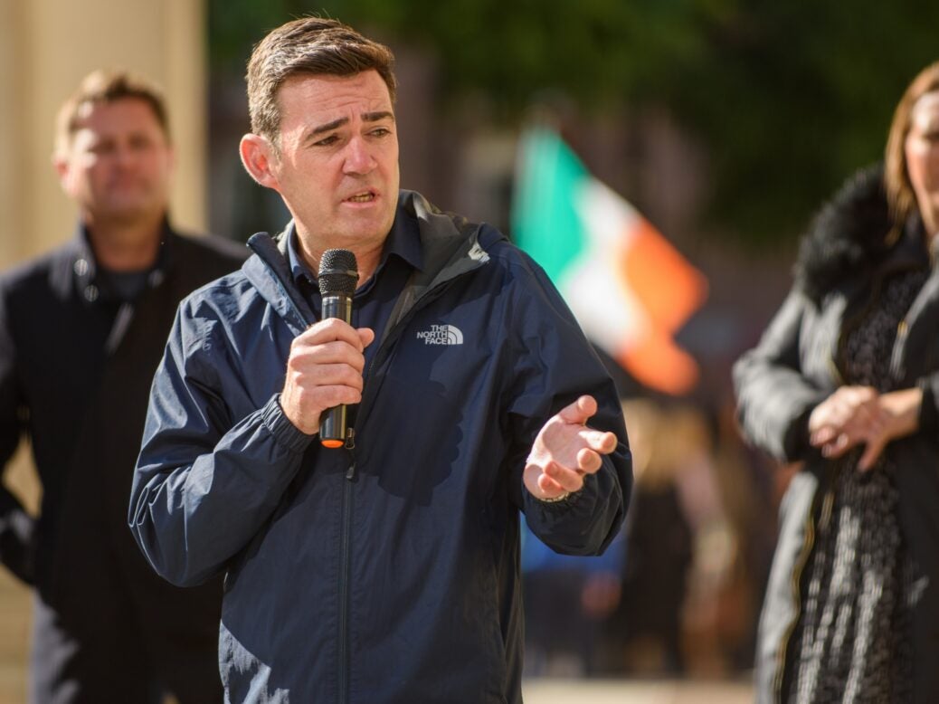 Andy Burnham speaking with a microphone outside a Conservative party conference in Manchester, 2021.