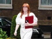 Angela Rayner pictured walking holding red folder wearing white dress and black glasses