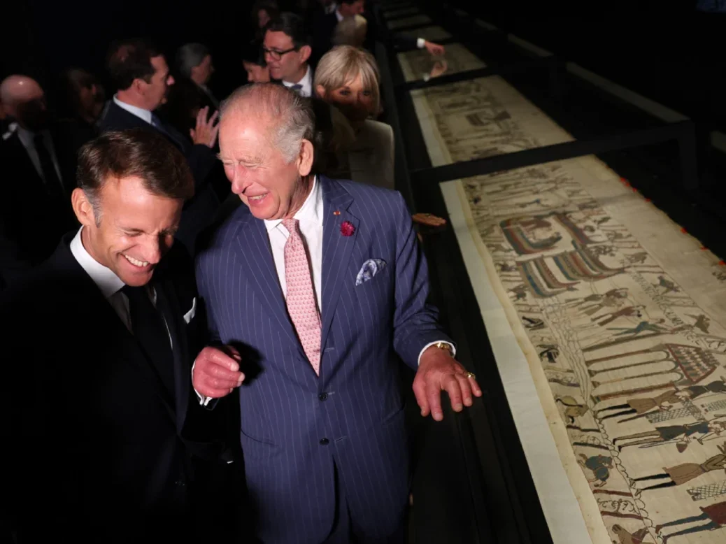 French President Emmanuel Macron and King Charles III laugh as they view a section of the Bayeux Tapestry Exhibition at the British Museum