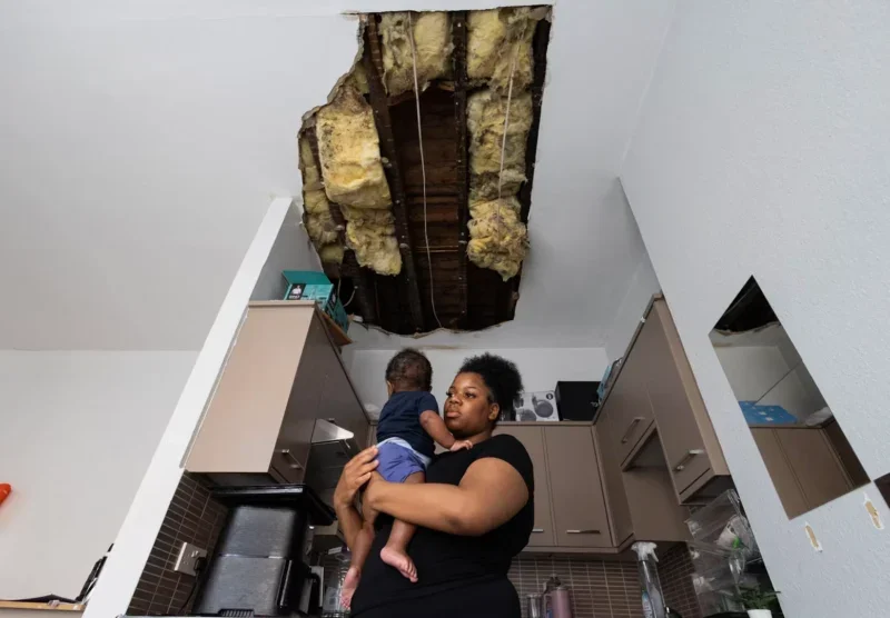 Image of woman holding child with huge hole in ceiling above them