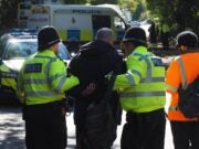 A photo of two policemen escorting a man wearing handcuffs.